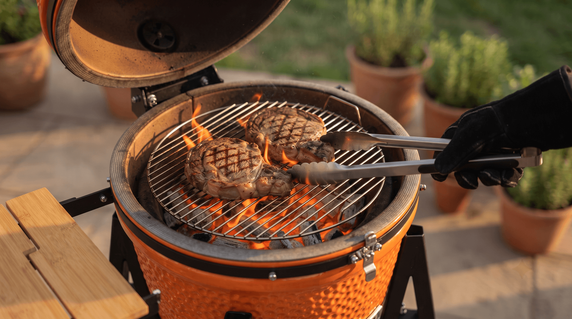 Two ribeyes searing on a small stainless grate over glowing lump charcoal in a ceramic kamado